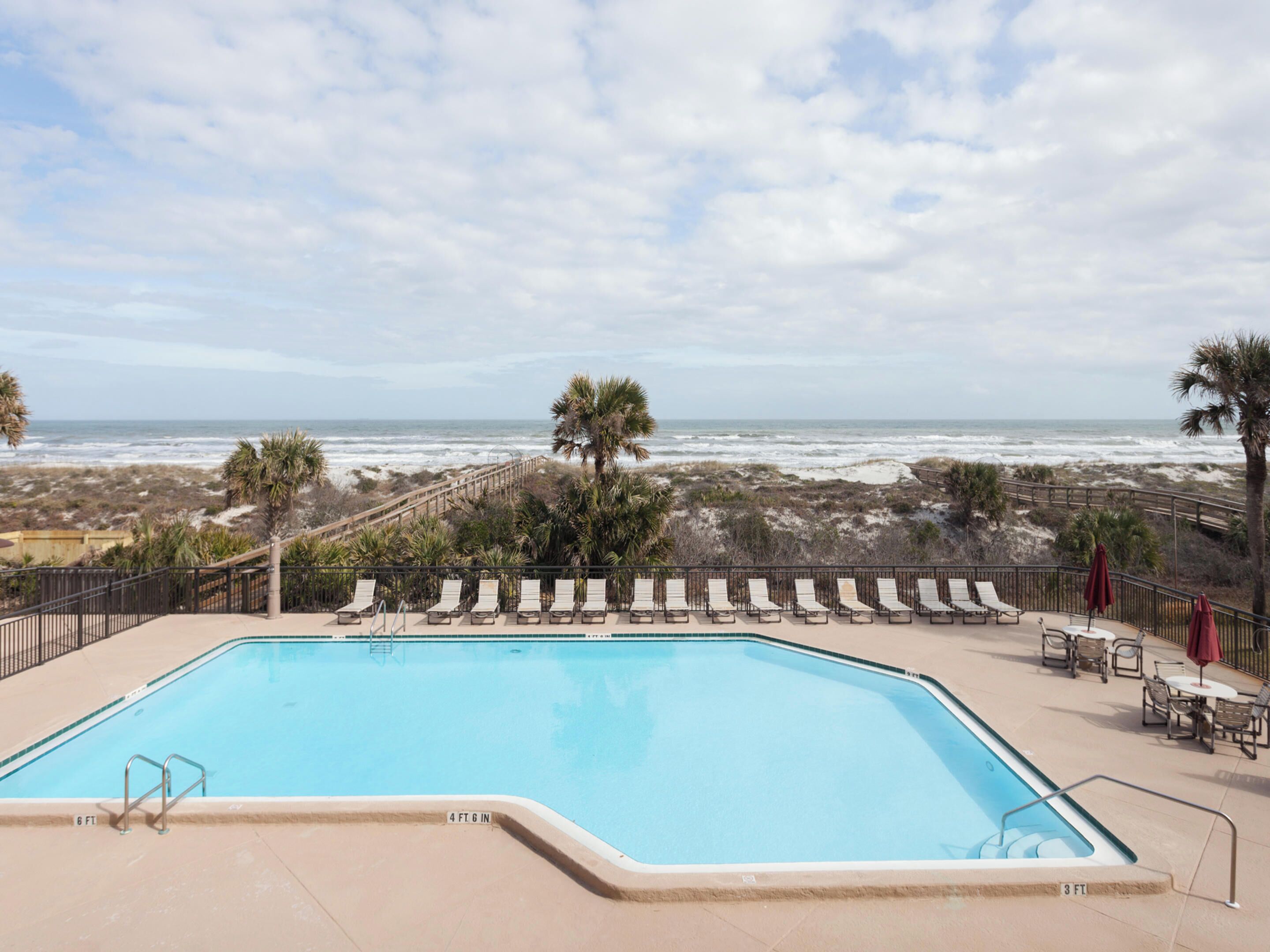 Ein Schwimmbecken mit Blick auf Strand und Meer.