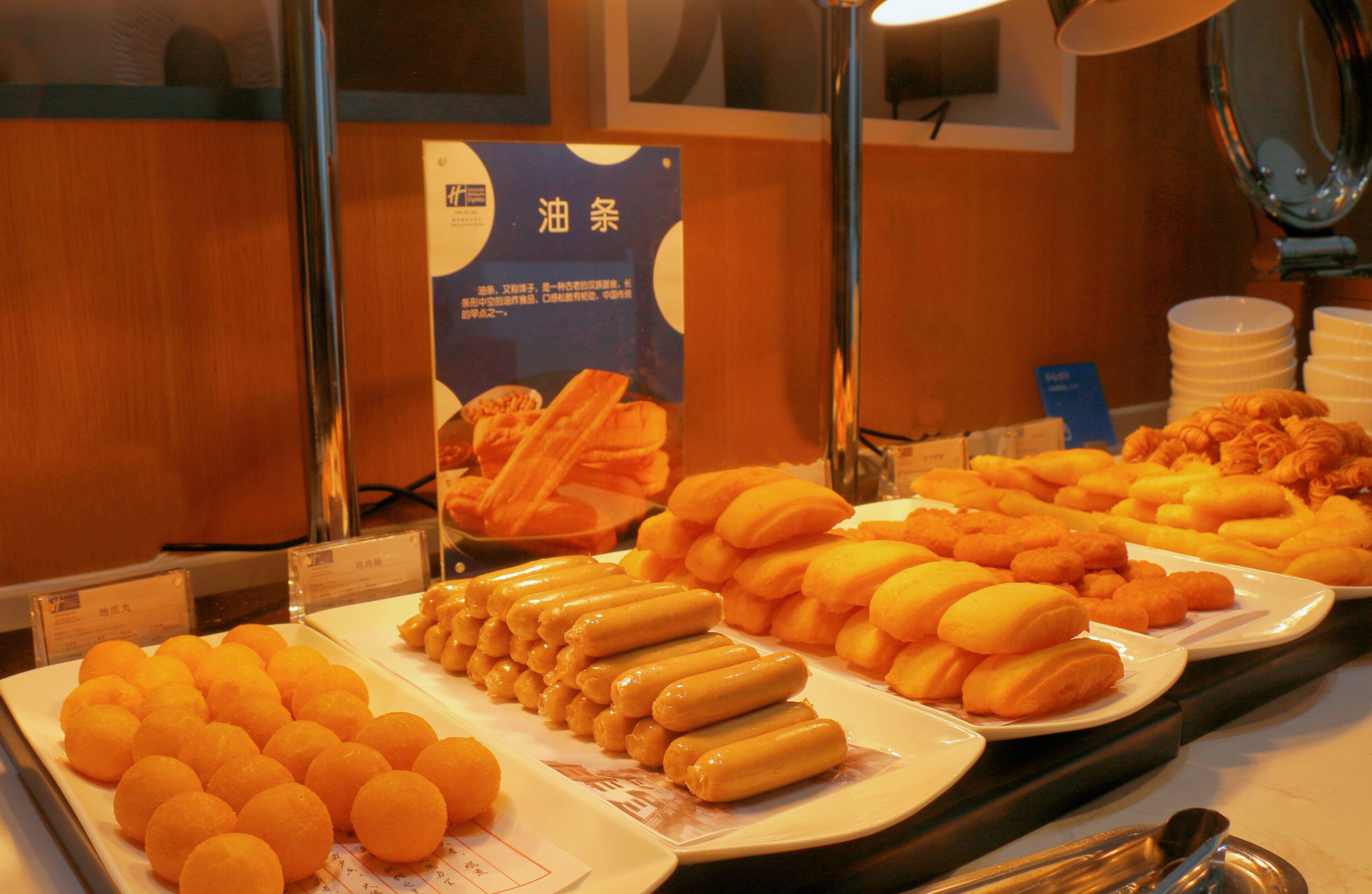 Un bufé con diferentes opciones de comida, incluyendo hot dogs y pasteles.