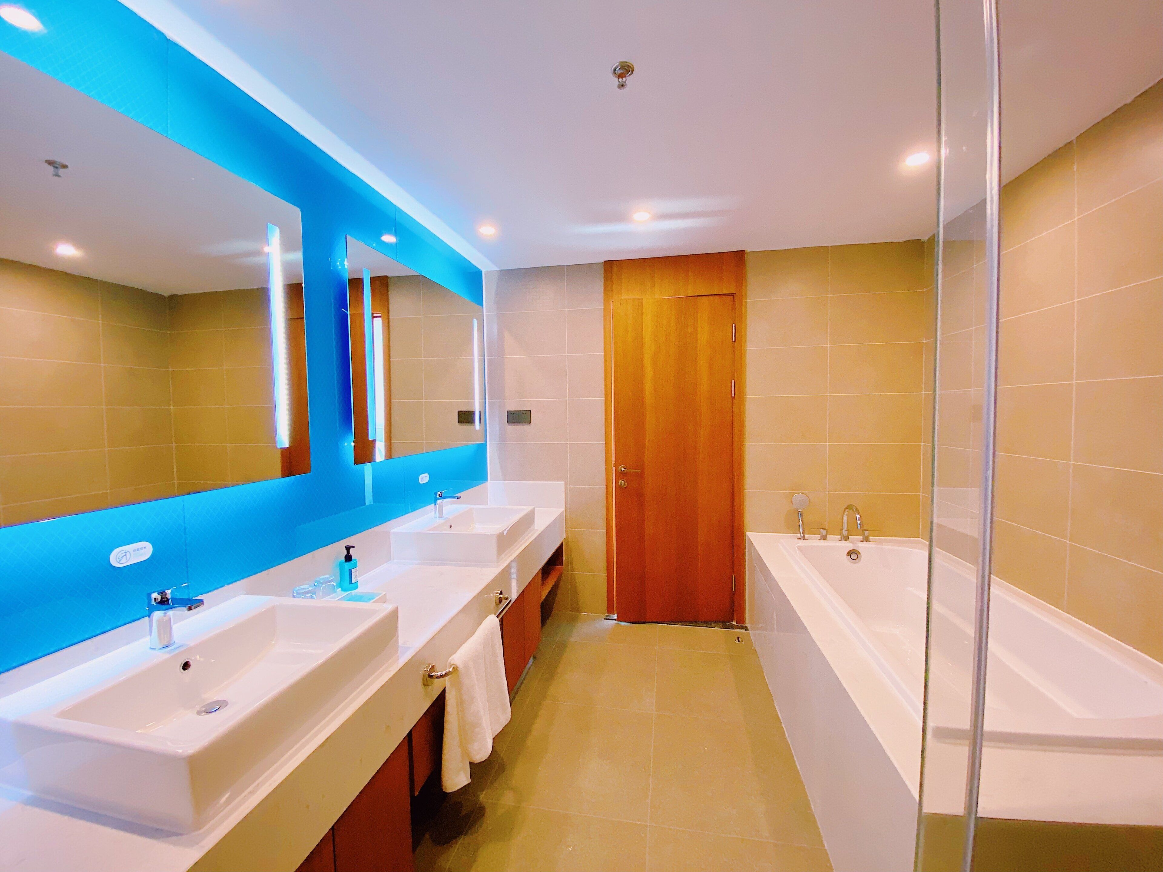 Un baño moderno con dos lavamanos, un espejo grande y una bañera.