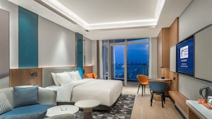 Una habitación de hotel moderna con una cama grande, un sofá, un escritorio y un televisor.