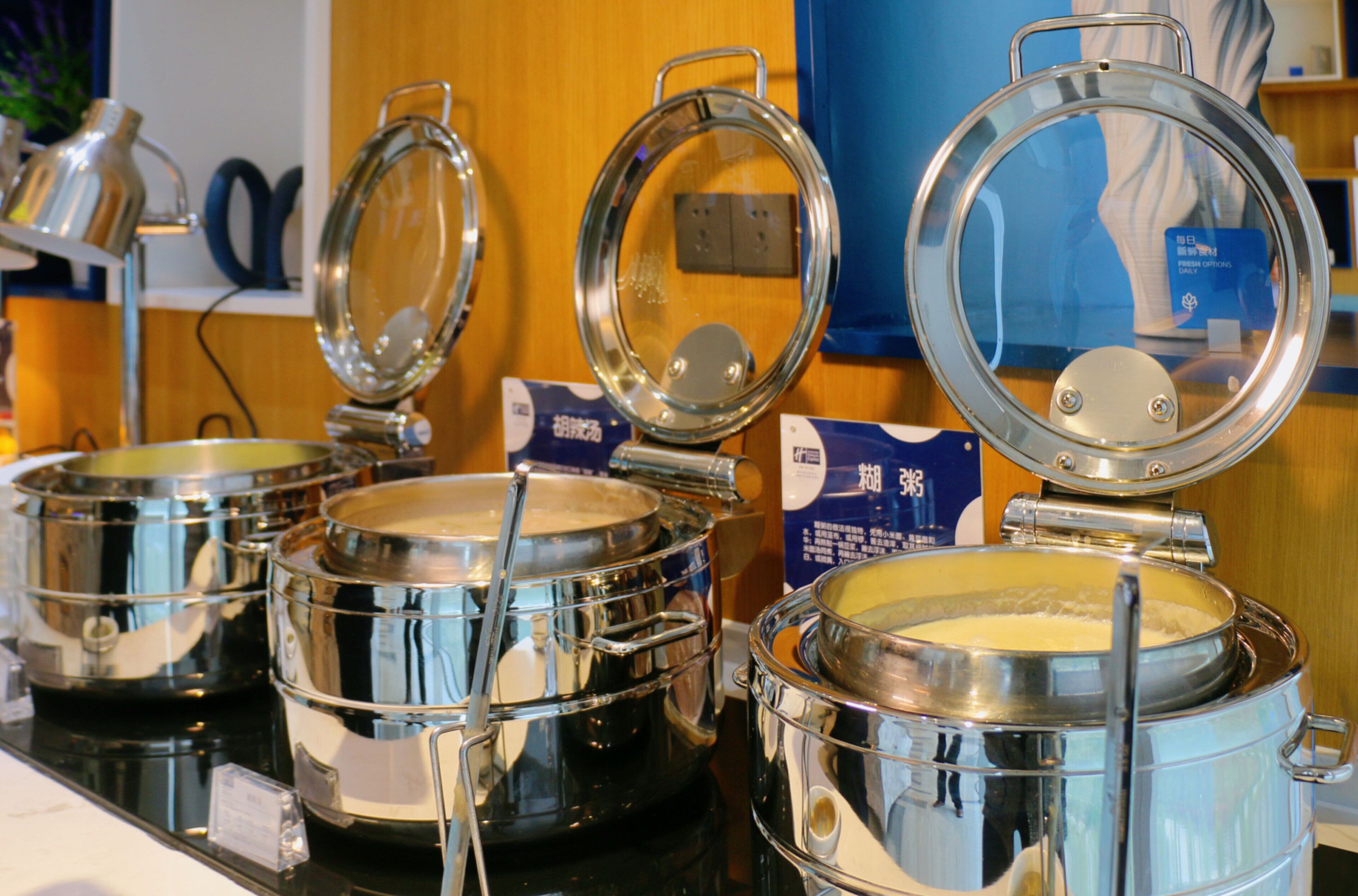 Stainless steel buffet bowls with lids, placed on a counter.