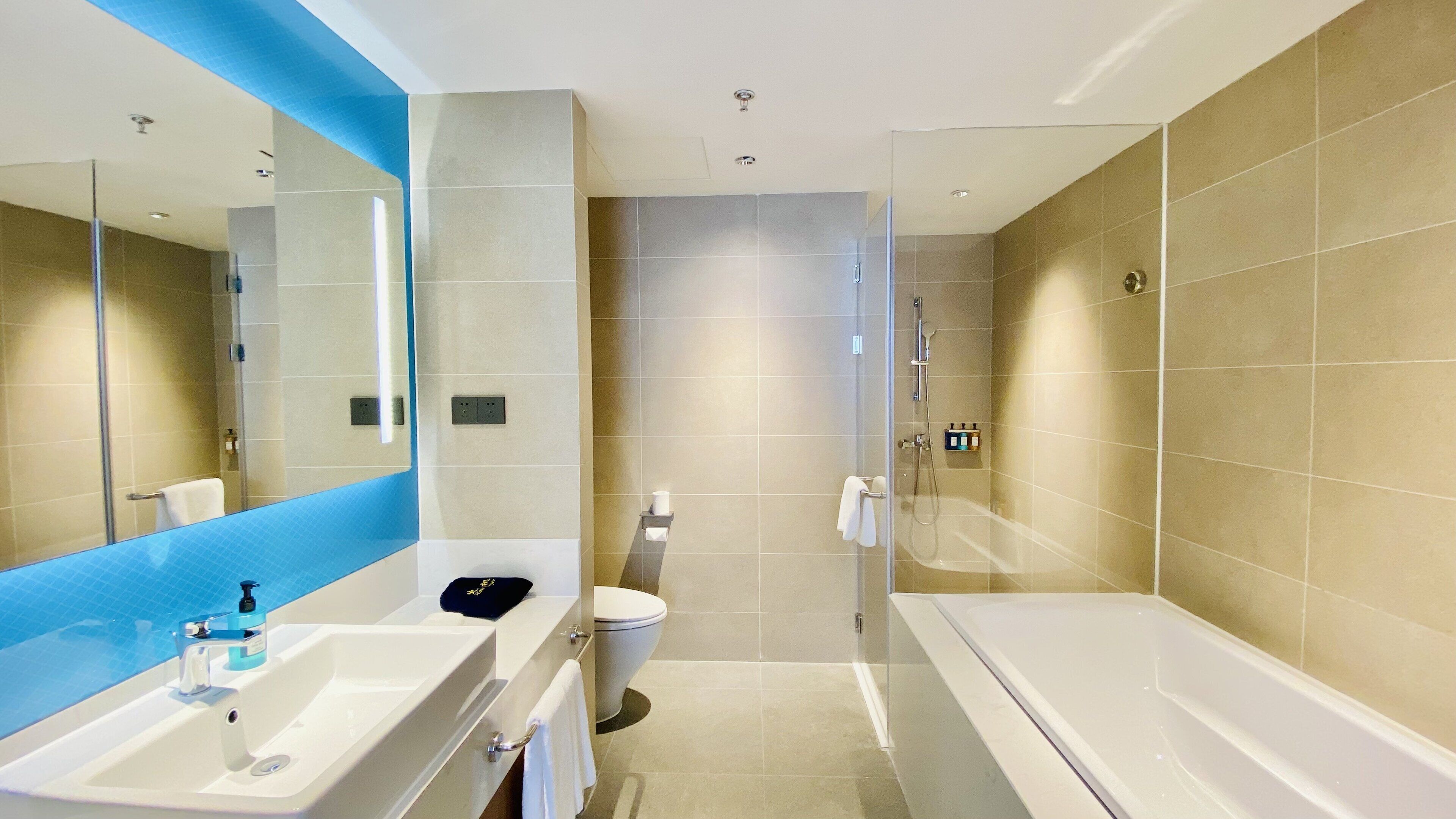 Un baño moderno con un espejo grande, una bañera, una ducha y un inodoro.