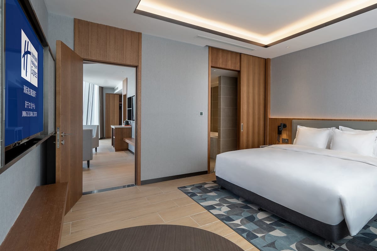 A modern hotel room with a large bed, a desk, and a television.