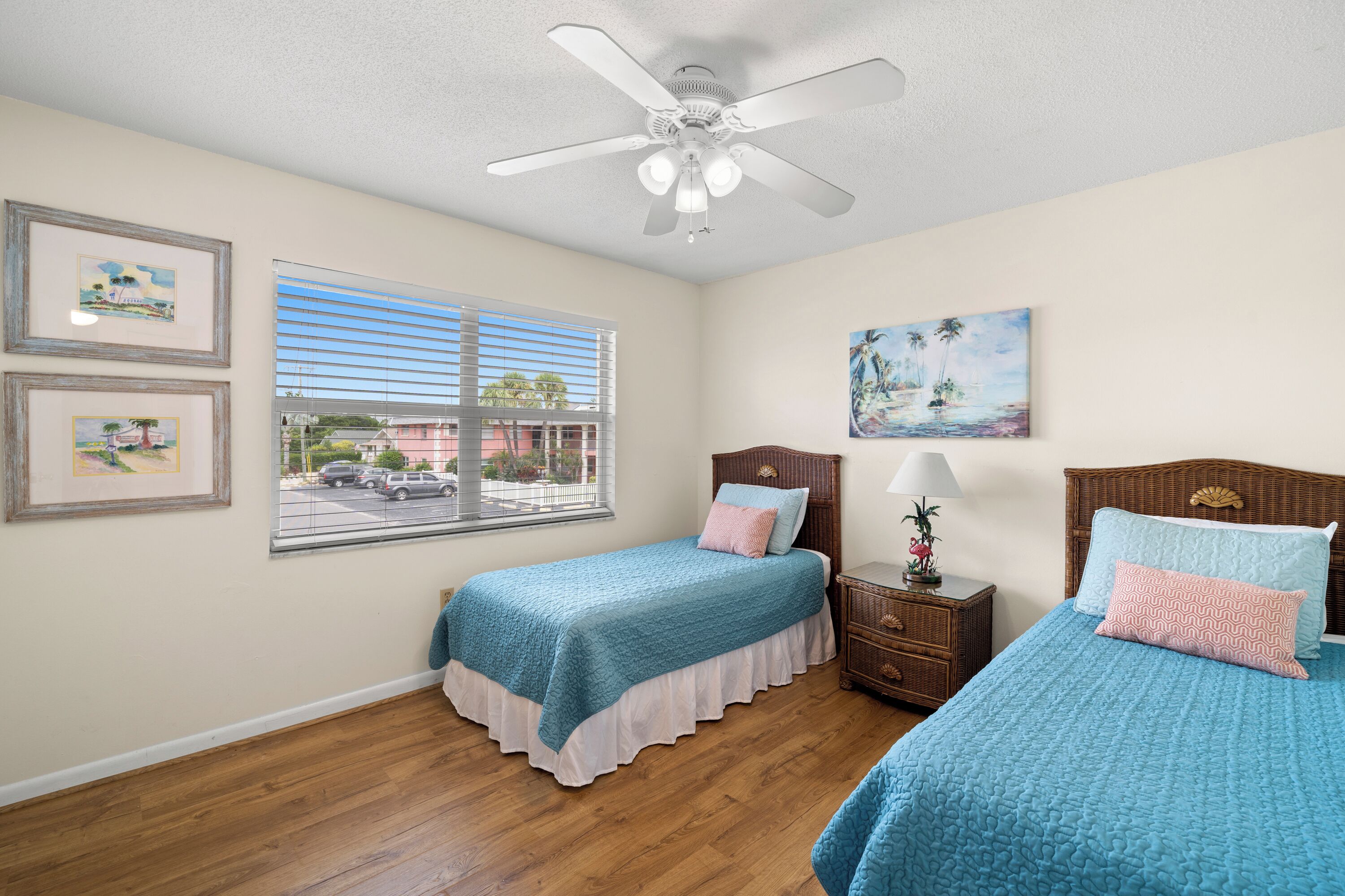 A bedroom with two beds, a ceiling fan, and a window with blinds.