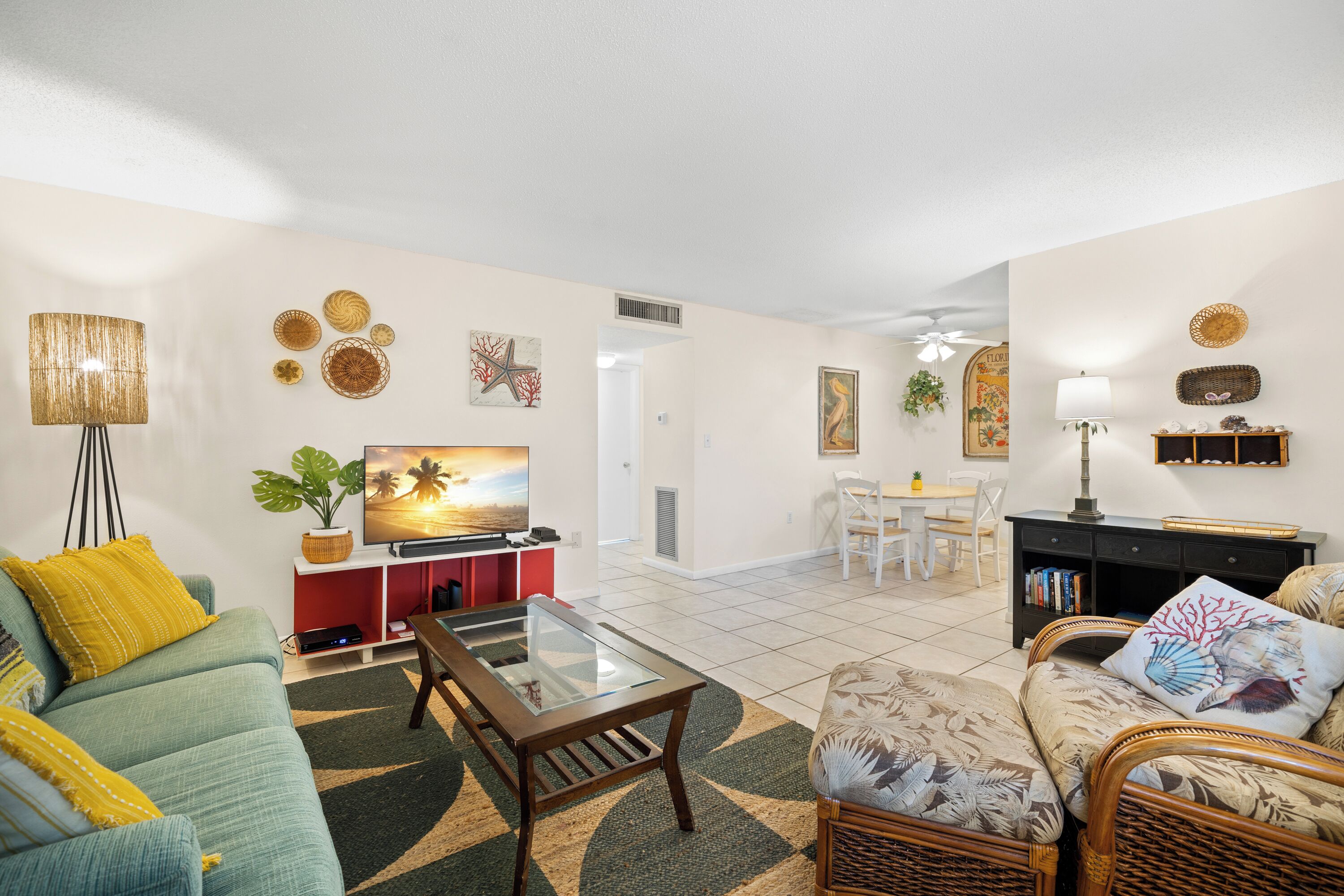 A living room with a sofa, a coffee table, a TV, and a dining area with chairs and a table.
