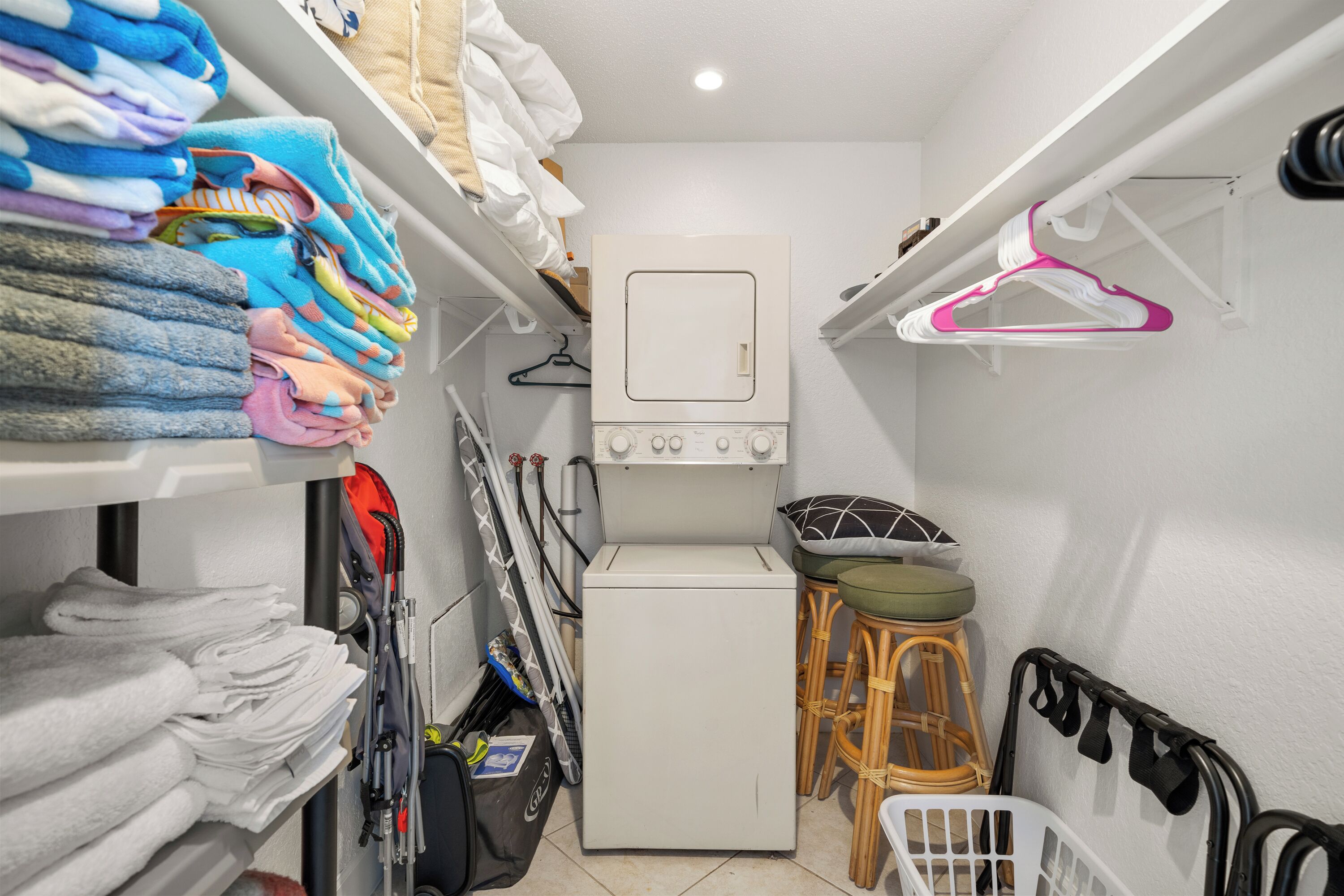 A laundry room with a washing machine, stacked towels, and a drying rack.