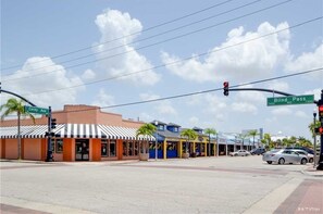 A street intersection with storefronts, a traffic light, and street signs for Corey Ave and Blind Pass Rd. - Waves by Distinctive Beach Rentals (St. Pete Beach)
