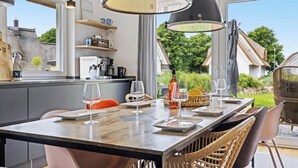 Uma cozinha moderna com uma ilha grande, uma área de refeições com cadeiras de vime e vista para o jardim.