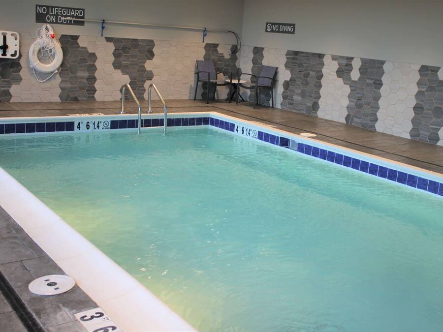 An indoor swimming pool with clear water, marked depth indicators, and safety signs.