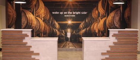 A reception area with a mural of barrels and a sign that reads "wake up on the bright side BARDSTOWN."
