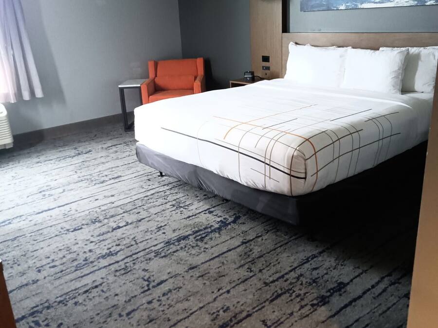 Una habitación de hotel con una cama grande, una silla, un escritorio y un cuadro en la pared.