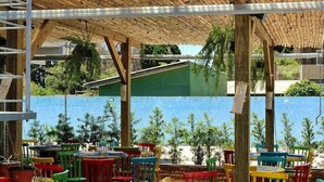 An outdoor seating area with colorful chairs and tables, a wooden deck, and a view of the sea. - Pousada Moçamba Dunas (Florianópolis)