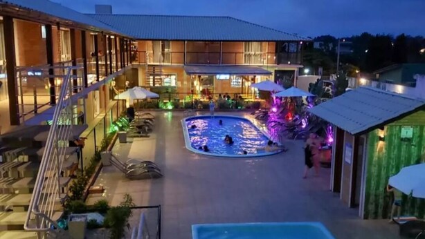 A hotel with a swimming pool, outdoor seating, and a covered area with umbrellas. - Pousada Moçamba Dunas (Florianópolis)