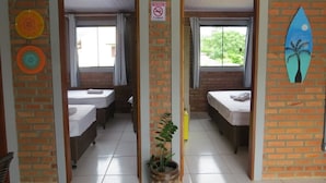 A room with two beds, a potted plant, and a surfboard decoration. - Pousada Moçamba Dunas (Florianópolis)