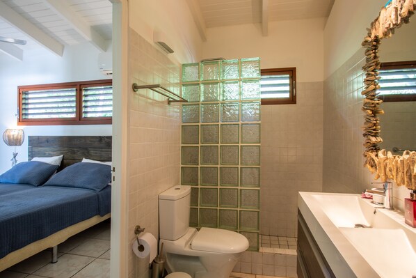 A bathroom with a glass shower enclosure, a toilet, and a sink with a mirror.