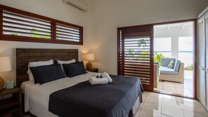Une chambre d’hôtel avec un grand lit, une table de chevet, une lampe et une vue sur le balcon.