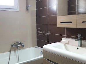 A bathroom with a bathtub, a sink, and a mirror.