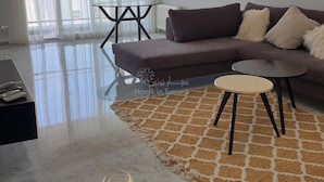 A modern living room with a dark brown sofa, a round coffee table, and a glass-top table. - Lovely, apparently feet in the water (sousse)