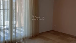 A room with a large window covered by sheer curtains, a tiled floor, and plain walls. - Lovely, apparently feet in the water (sousse)