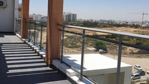 A balcony with a view of a construction site and buildings in the distance. - Lovely, apparently feet in the water (sousse)