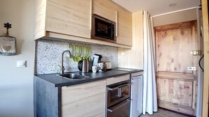Een kleine keuken met houten kastjes, een magnetron, een spoelbak en een vaatwasser.