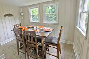 A dining room with a wooden table set for four, two windows, and a cityscape sign on the wall. - 4BR Getaway | King Bed | Prime Uptown-SouthEnd (Charlotte)