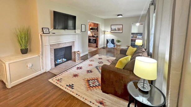 Una sala de estar con chimenea, televisor, sofá y comedor al fondo.