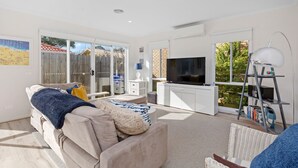 Un salón amplio con un sofá, un televisor y una estantería.