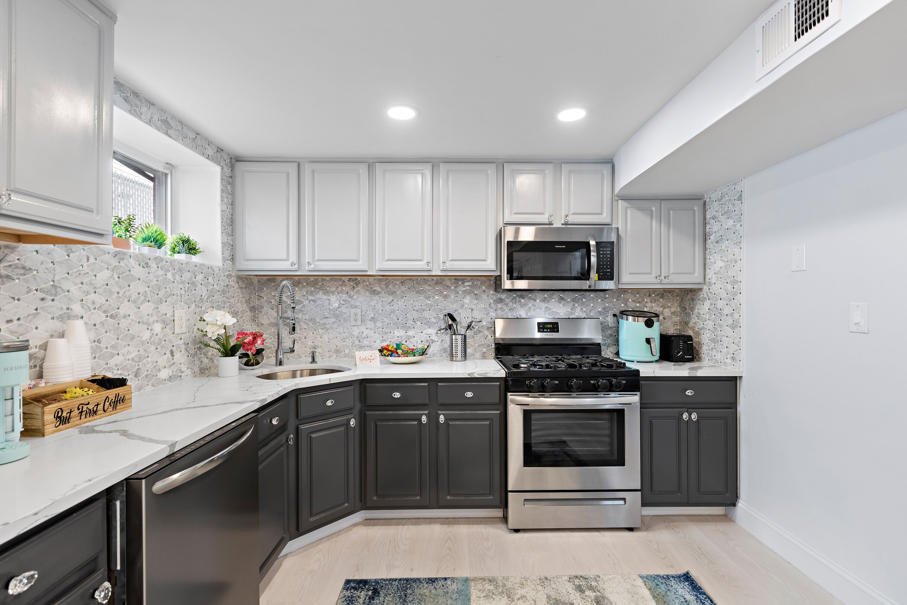 A modern kitchen with dark cabinets, a stainless steel stove, a microwave, and a granite countertop.