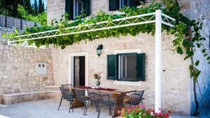 A stone building with a table and chairs outside, a white pergola, and a planter with flowers. - STONE HOUSES , COMPLETE PRIVACY , 7 BEDROOMS , 2 POOLS , IDEAL PLACE FOR HOLIDAY (kremena)