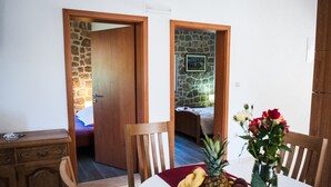 A room with a wooden desk, a dining table with fruit and flowers, and a bed with a stone wall and a painting. - STONE HOUSES , COMPLETE PRIVACY , 7 BEDROOMS , 2 POOLS , IDEAL PLACE FOR HOLIDAY (kremena)