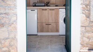 A compact kitchen with wooden cabinets, a dishwasher, and a washing machine. - STONE HOUSES , COMPLETE PRIVACY , 7 BEDROOMS , 2 POOLS , IDEAL PLACE FOR HOLIDAY (kremena)