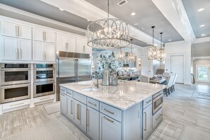 A spacious kitchen with a large island, stainless steel appliances, and modern lighting fixtures.