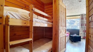 A wooden cabin with bunk beds, a small table, and a view of the mountains. - Ski-in/ski-out & foot of the slopes, 2nd floor, balcony, tv, 20m², Les Menuires (Les Menuires)