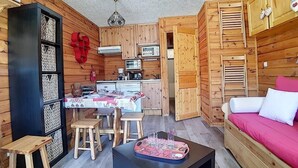 A compact wooden cabin with a dining area, kitchenette, and a bed. - Ski-in/ski-out & foot of the slopes, 2nd floor, balcony, tv, 20m², Les Menuires (Les Menuires)