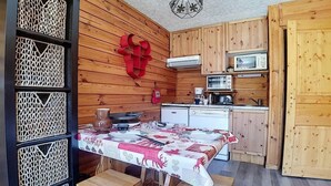 A wooden interior with a dining table set for four, a microwave, and a small kitchen area. - Ski-in/ski-out & foot of the slopes, 2nd floor, balcony, tv, 20m², Les Menuires (Les Menuires)