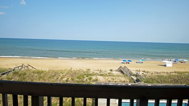 Une plage avec une terrasse en bois et une piscine.