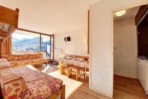 A cozy room with a bed, a dining table, and a view of the mountains. - At the foot of shops, 5th floor, view ski slopes, balcony, tv, ski locker, 36m², Les Menuires (Les Menuires)