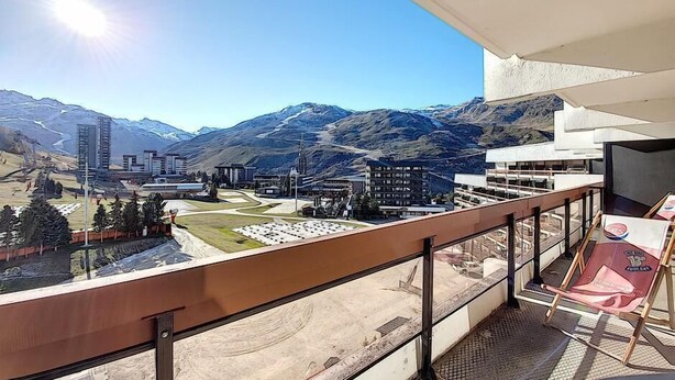 Un balcón con vistas a un paisaje montañoso, edificios y cielo despejado.