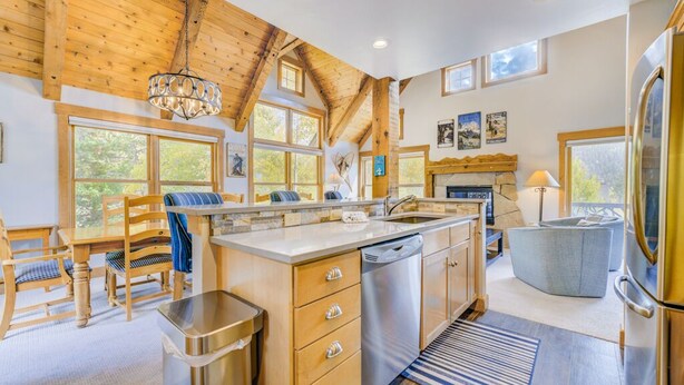 A modern kitchen with wooden beams, a large island, and a view of the outdoors.