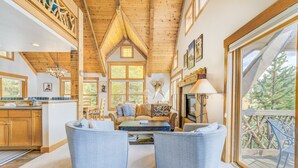 A cozy interior with a wooden ceiling, a fireplace, and a balcony with a view of trees.