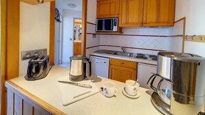 Eine kleine Küche mit Holzausstattung, einer Mikrowelle, einem Wasserkocher, einem Toaster und einer Kaffeemaschine.