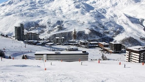 A snow-covered ski resort with modern buildings, ski slopes, and a mountain backdrop. - 100m from ski slopes, 7th floor, view mountain, balcony, tv, ski locker, 36m², Les Menuires (Les Menuires)