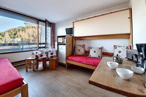 A compact room with a bunk bed, a dining table, and a small kitchen area.