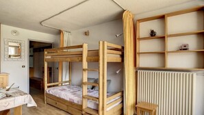 A dormitory room with bunk beds, a small table, a chair, and a radiator. - 100m from ski slopes, 3rd floor, balcony, tv, ski locker, 24m², Les Menuires (Les Menuires)