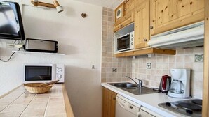 A compact kitchen with a microwave, toaster, and coffee maker. - 100m from ski slopes, 3rd floor, balcony, tv, ski locker, 24m², Les Menuires (Les Menuires)