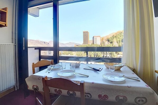 Enjoy meals in this stylish dining area with a table for four, overlooking a cityscape with distant hills.