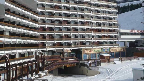 Un hotel de varios pisos con balcones, un telesilla y un restaurante.