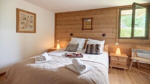Une chambre confortable avec une tête de lit en bois, une table de chevet avec une lampe et une fenêtre donnant sur un paysage verdoyant.