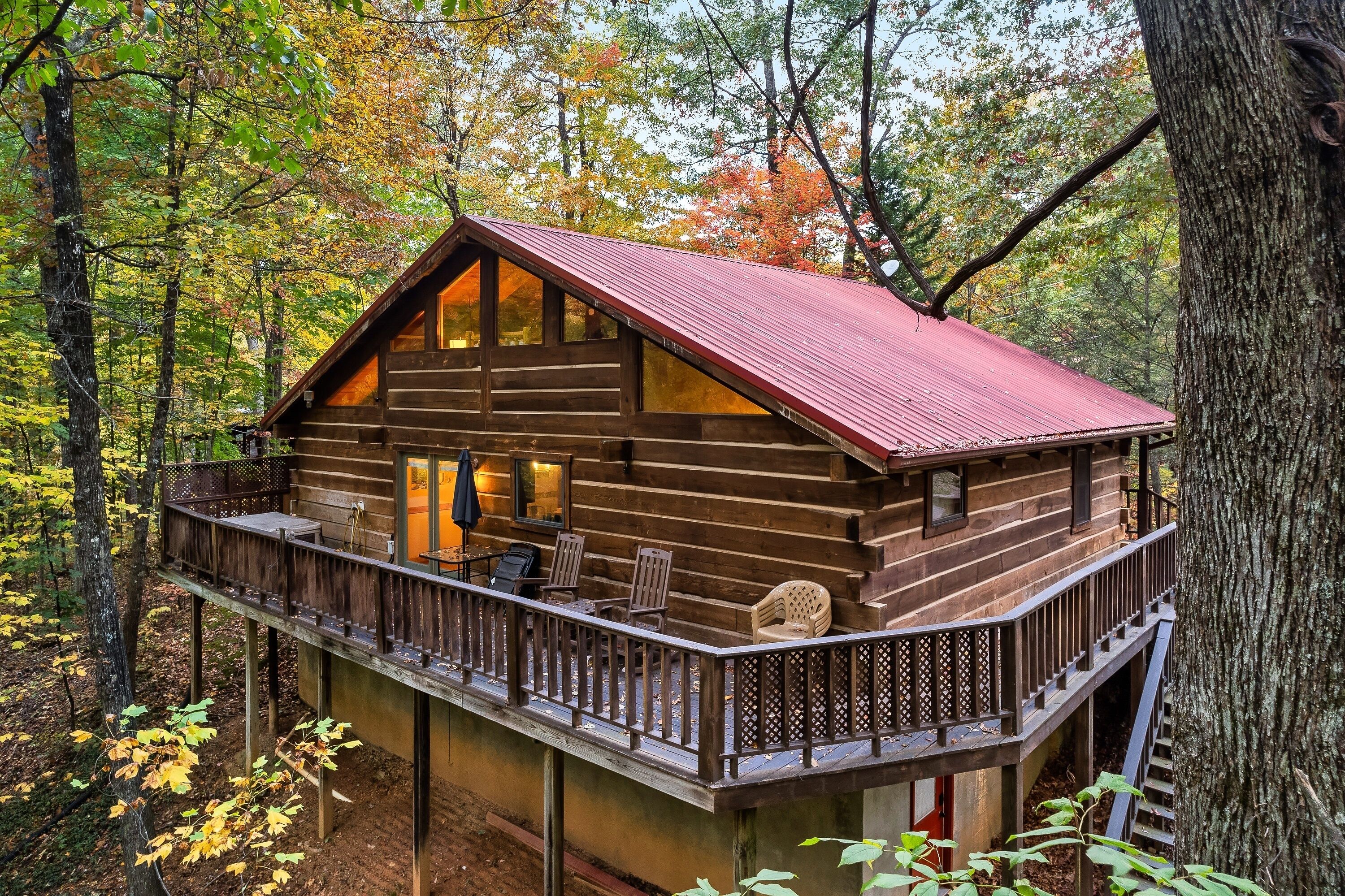 A wooden cabin with a balcony, surrounded by trees.
